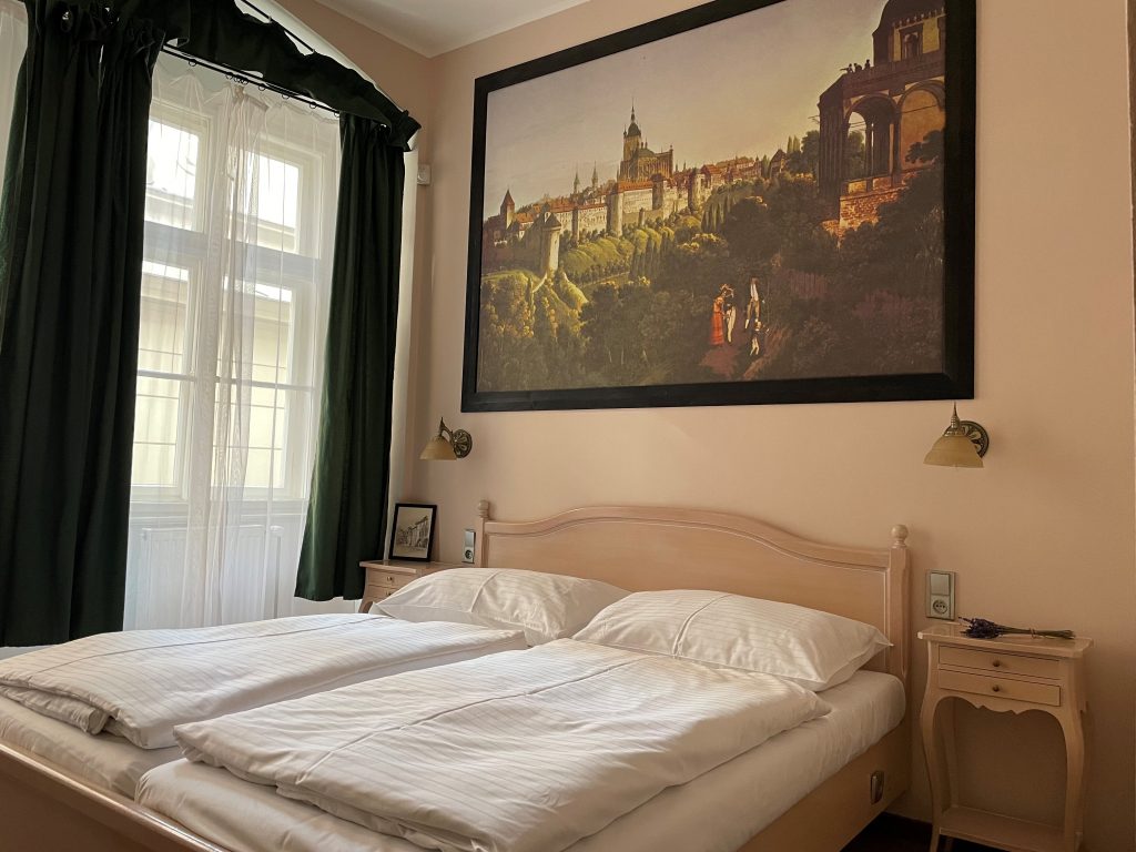 Manželská postel s nočními stolky a obrazem na stěně